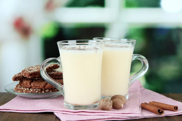 Copas de ponche de huevo con canela y galletas en la mesa sobre fondo brillante — Foto de Stock