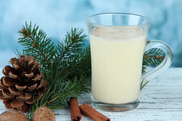 Cup of eggnog with fir branches on table on bright background — Stock Photo, Image