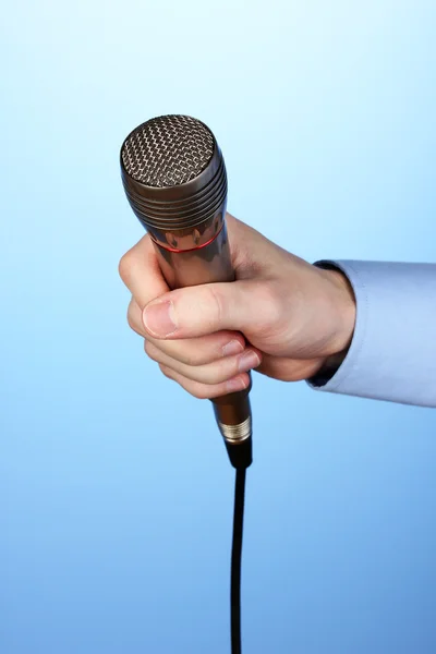 Mano maschile con microfono su sfondo blu — Foto Stock
