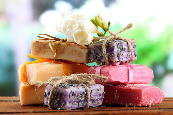 Естественное мыло ручной работы, на деревянном столе, на зеленом фоне
