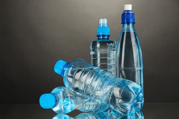 Différentes bouteilles d'eau sur fond gris — Photo