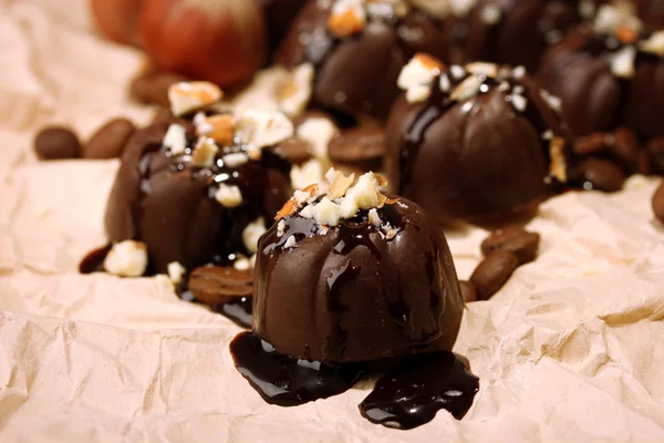 Caramelle al cioccolato e chicchi di caffè, su sfondo di carta beige — Foto Stock