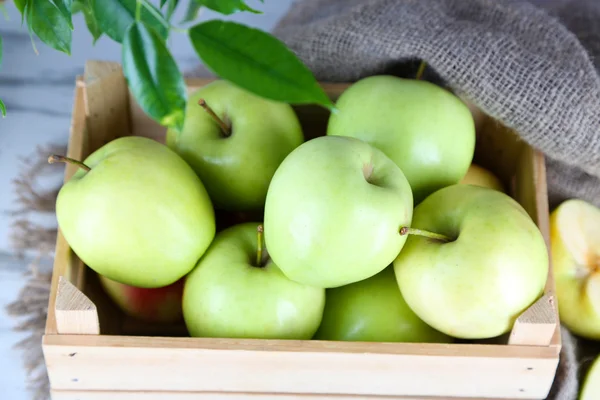 Juicy apples in box on wooden table — Stock Photo, Image