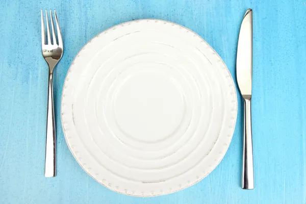 Plate and cutlery on wooden table close-up — Stock Photo, Image