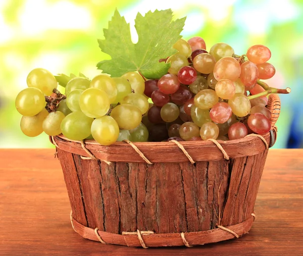 Спелый сладкий виноград в корзине на деревянном столе, на природе — стоковое фото