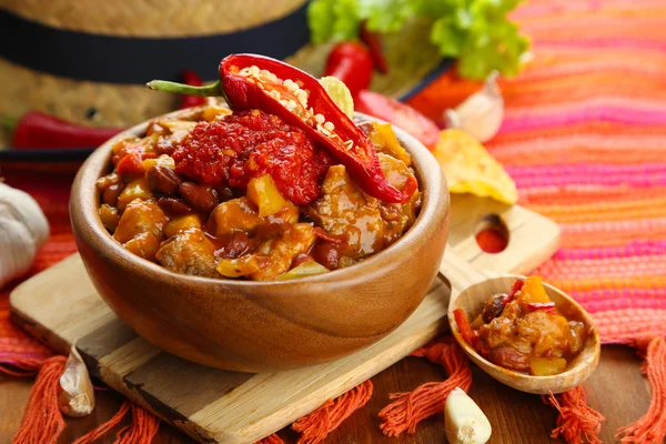 Carne de maíz con chile - comida tradicional mexicana, en tazón de madera, en servilleta, sobre fondo de madera — Foto de Stock