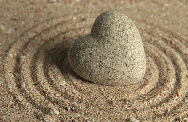 灰色の砂の背景にハートの形で禅石 — ストック写真