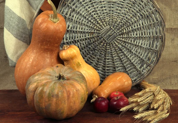 Zucche con mele e covone su tavola di legno su fondo sacco — Foto Stock