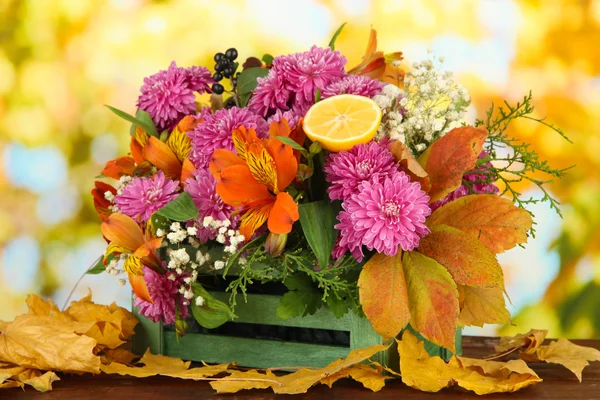 Composition des fleurs en caisse avec des feuilles jaunes sur la table sur fond lumineux — Photo