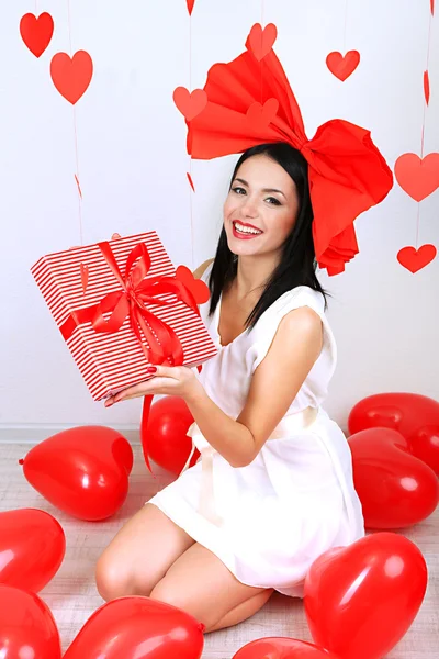 Attraente giovane donna con regalo e palloncini in camera a San Valentino — Foto Stock