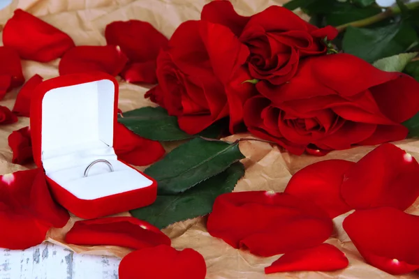 Кольцо окружено розами и лепестками на деревянном столе крупным планом — стоковое фото