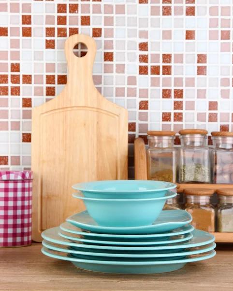 Plates in kitchen on table on mosaic tiles background — Stock Photo, Image