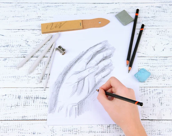 Dessine à la main un croquis avec des matériaux d'art professionnels, sur une table en bois — Photo