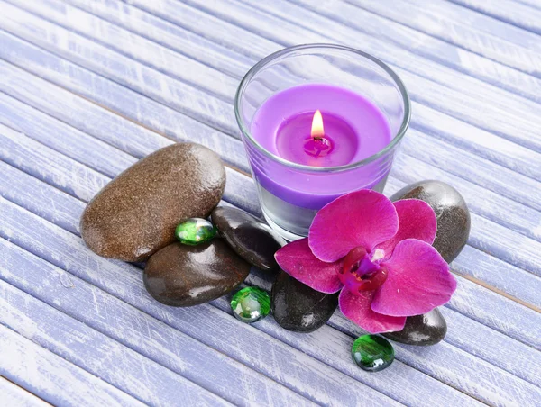 Schöne bunte Kerzen und Orchideenblume, auf farbigem Holzhintergrund — Stockfoto