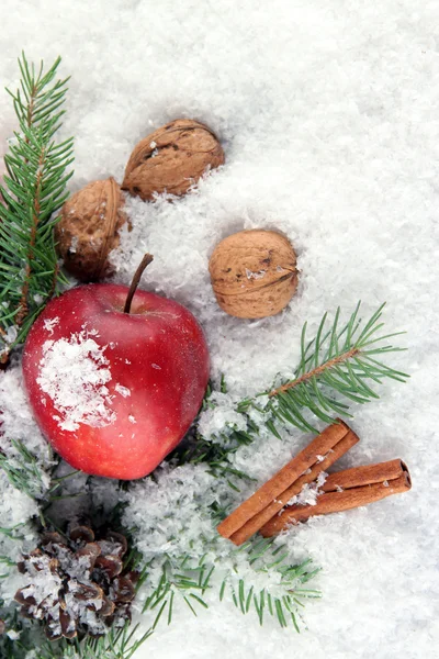 Manzana roja con ramas de abeto en nieve de cerca —  Fotos de Stock