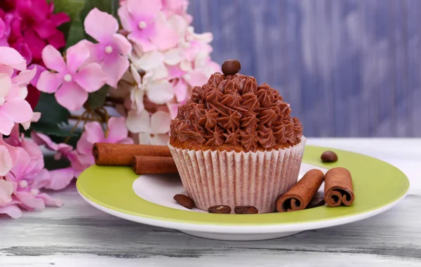 Välsmakande cupcake med smörkräm, på plattan, färg trä bakgrund — Stockfoto