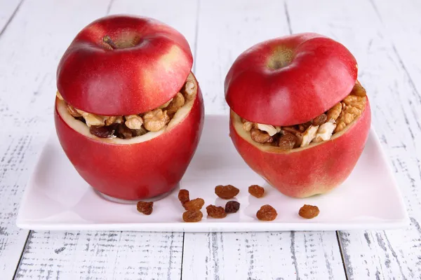 Äpplen med russin och nötter på plattan på trä bakgrund — Stockfoto