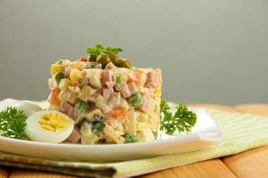 geleneksel Rus salatası olivier, tahta masada gri arka plan üzerinde renkli peçete üzerinde
