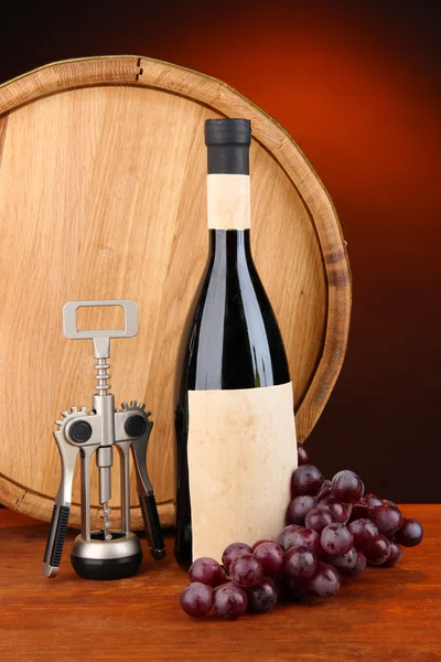Zusammensetzung aus Korkenzieher und Flasche Wein, Traube, Holzfass auf Holztisch auf dunklem Hintergrund — Stockfoto