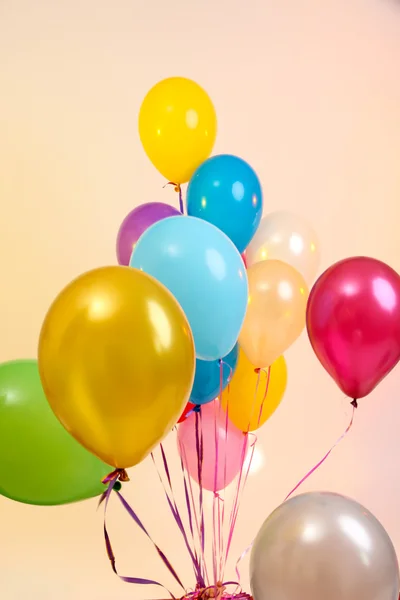 Viele helle Luftballons auf orangefarbenem Hintergrund — Stockfoto
