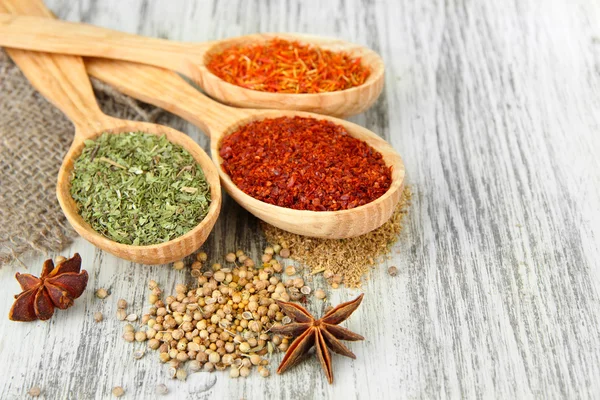 Assortment of spices in wooden spoons on wooden background — Stock Photo, Image