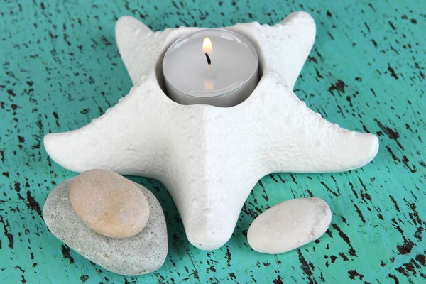 Candle in starfish with decor on blue wooden table — Stock Photo, Image