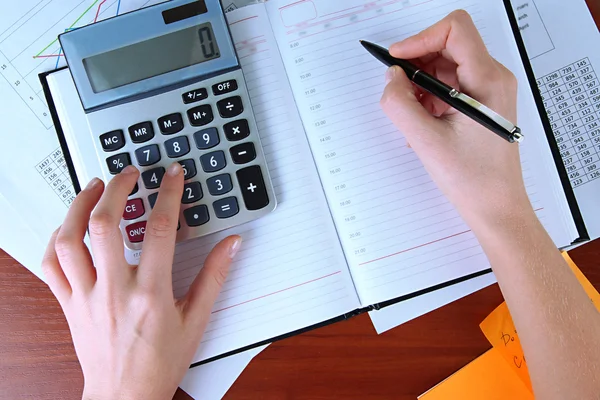 Mujer manos contando con calculadora en fondo de mesa de trabajo — Foto de Stock