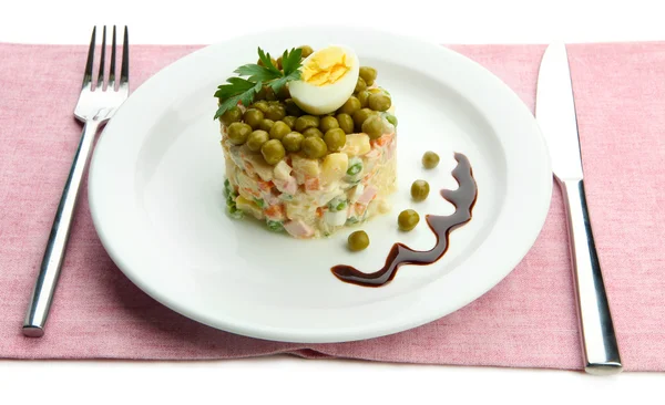 Russische traditionele salade olivier op witte plaat, op kleur servet, geïsoleerd op wit — Stockfoto