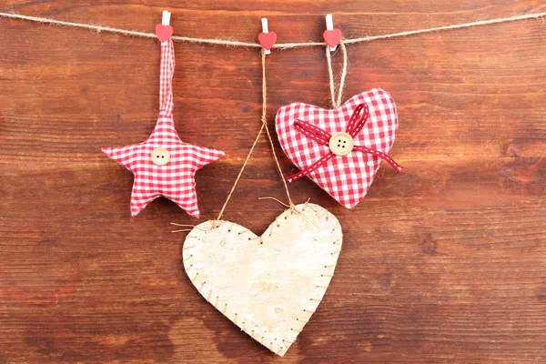Coração decorativo e estrela na corda, no fundo de madeira — Fotografia de Stock