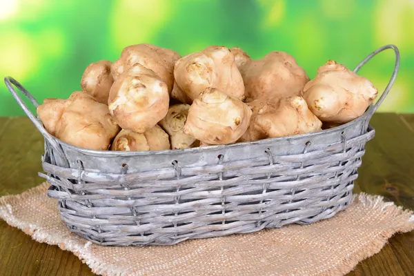 Topinambur roots in wicker basket on table on bright background — Stock Photo, Image