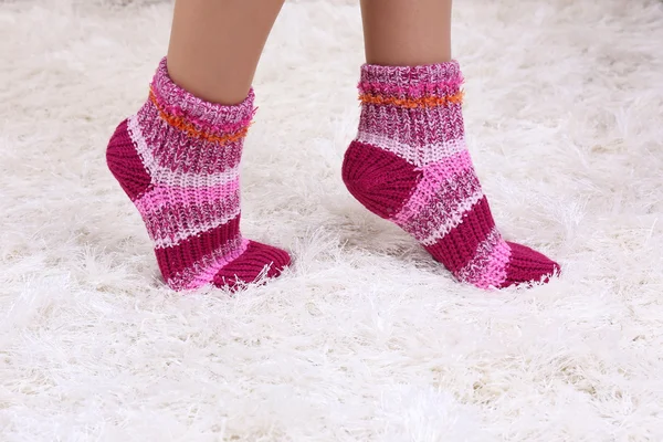 Patas femeninas en calcetines de colores sobre fondo de alfombra blanca —  Fotos de Stock