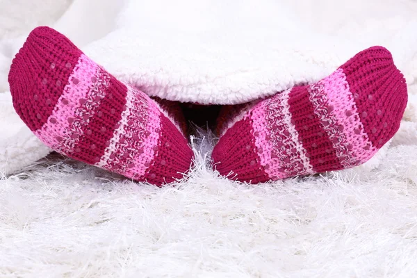 Patas femeninas en calcetines de colores sobre fondo de alfombra blanca —  Fotos de Stock