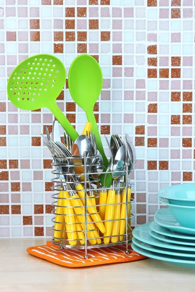 Platos y cubiertos en la cocina en la mesa en el fondo de azulejos de mosaico —  Fotos de Stock