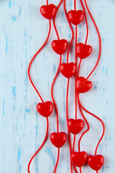 Heart-shaped beads on string on wooden background — Stock Photo, Image