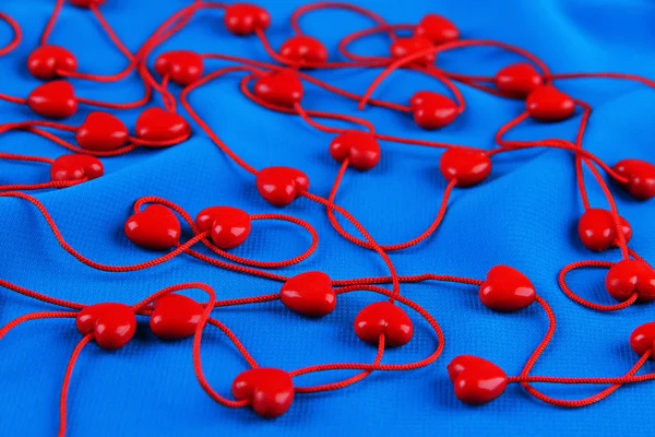 Heart-shaped beads on string on fabric background — Stock Photo, Image