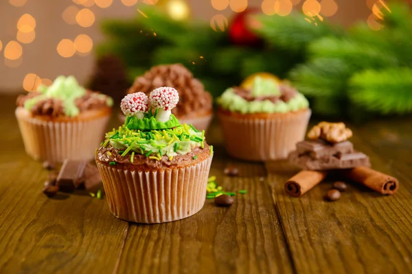 Gustosi cupcake con crema di burro, su tavolo di legno, su sfondo luminoso — Foto Stock