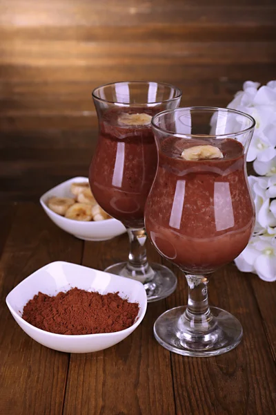 Coquetéis com banana e chocolate na mesa em fundo de madeira — Fotografia de Stock