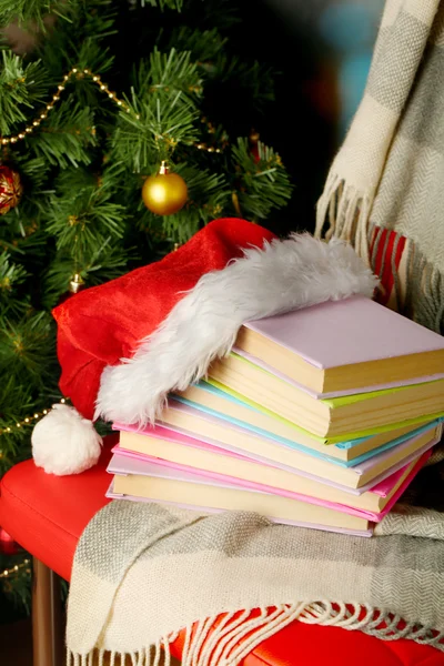 Composição com livros e xadrez, chapéu vermelho, na cadeira no fundo da árvore de Natal — Fotografia de Stock