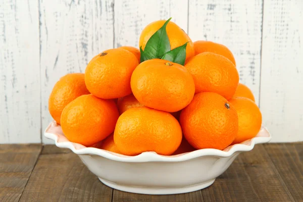 Zralé mandarinky v misce na tabulce na dřevěné pozadí — Stock fotografie