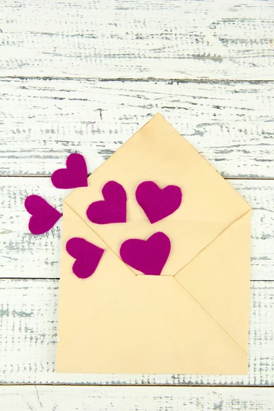 Beautiful old envelope with decorative hearts on wooden background — Stock Photo, Image