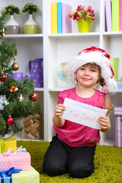 Kleines Mädchen mit Weihnachtsmann-Brief in der Nähe des Weihnachtsbaums im Zimmer — Stockfoto