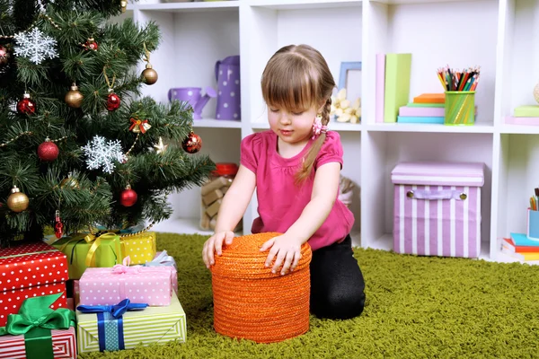 Menina sentada perto da árvore de Natal no quarto — Fotografia de Stock