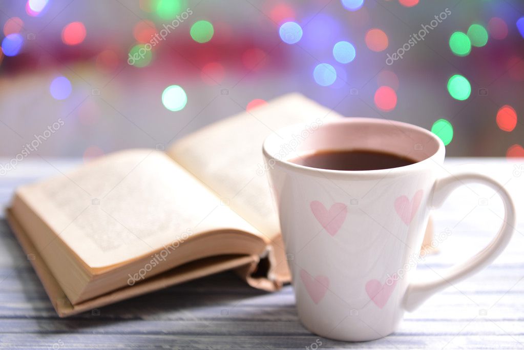 Composition of book with cup of coffee on table on bright background