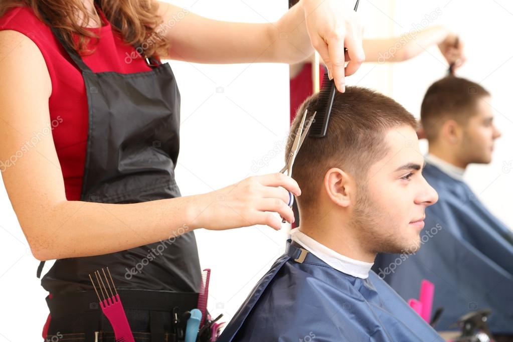 Beautiful girl hairdresser cut guy in beauty salon