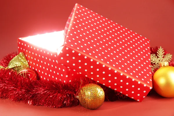 Подарункова коробка з яскравим світлом на ньому на червоному тлі — стокове фото
