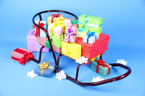 Санки с рождественскими подарками на голубом фоне — стоковое фото