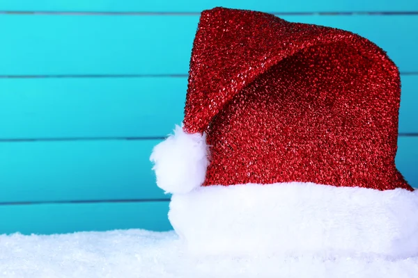 Santa hat on snow on color wooden background — Stock Photo, Image