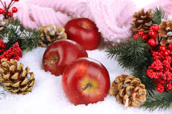 Manzanas rojas con ramas de abeto y bufanda de punto en la nieve de cerca —  Fotos de Stock
