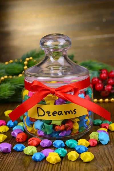 Paper stars with dreams in jar on table on wooden background — Stock Photo, Image