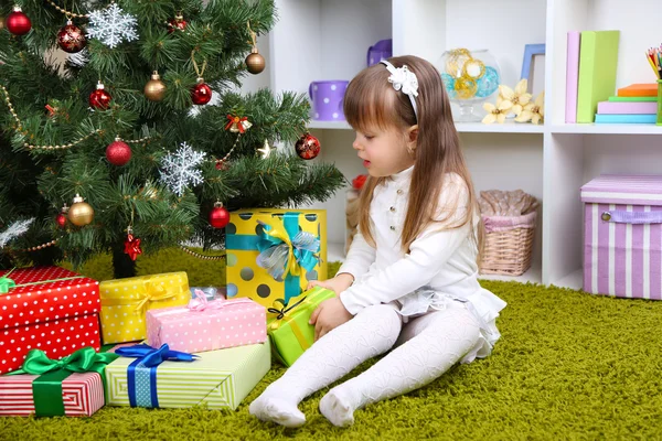 Little girl with present box near Christmas tree in room — Stock Photo, Image